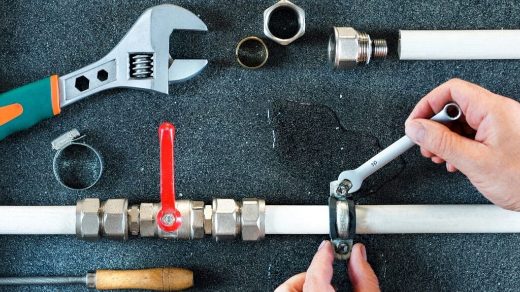 Plumber repairing a pipe valve with an adjustable wrench in San Bernardino