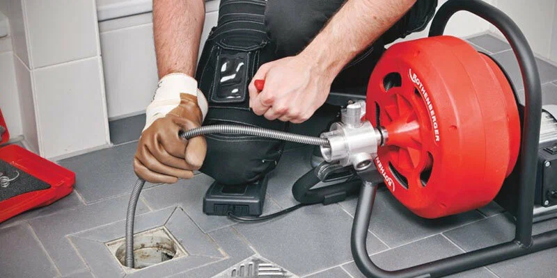 Plumber using a drain-cleaning machine in San Bernardino