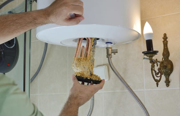 Technician removing mineral buildup from a water heater in San Bernardino