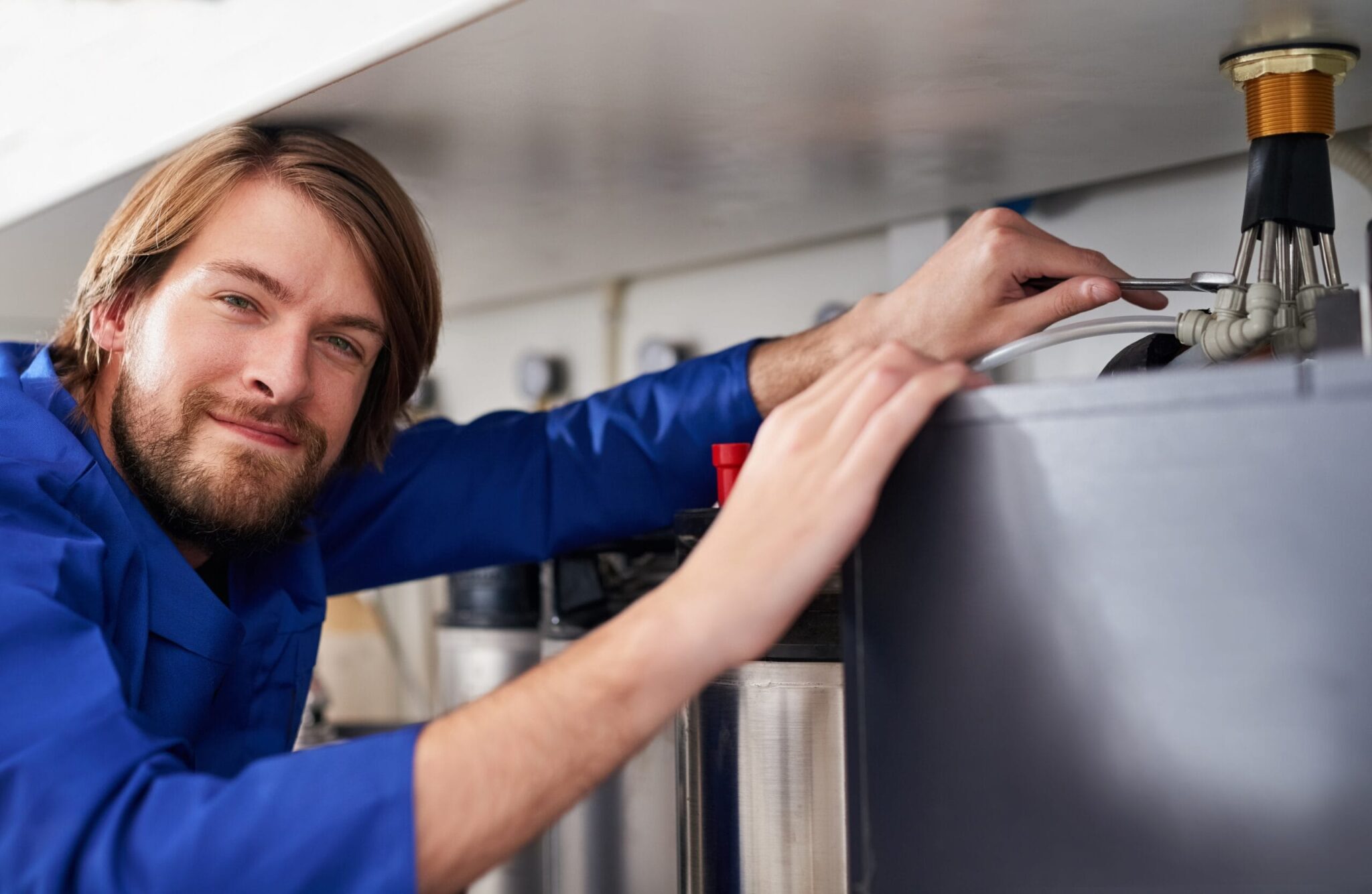 Technician servicing a residential water heater tank in San Bernardino