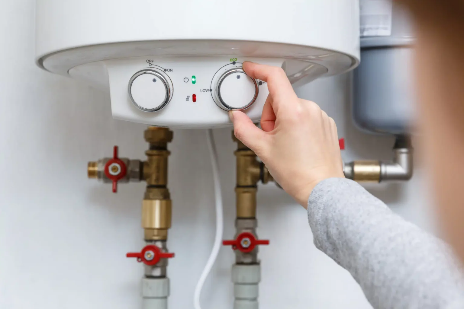 Homeowner adjusting the temperature controls on a water heater in San Bernardino